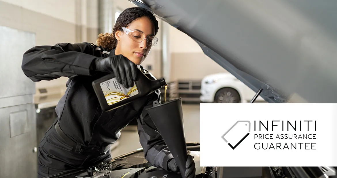 INFINITI technician under the hood of a vehicle adding oil. Image also includes the INFINITI Price Assurance Guarantee logo.