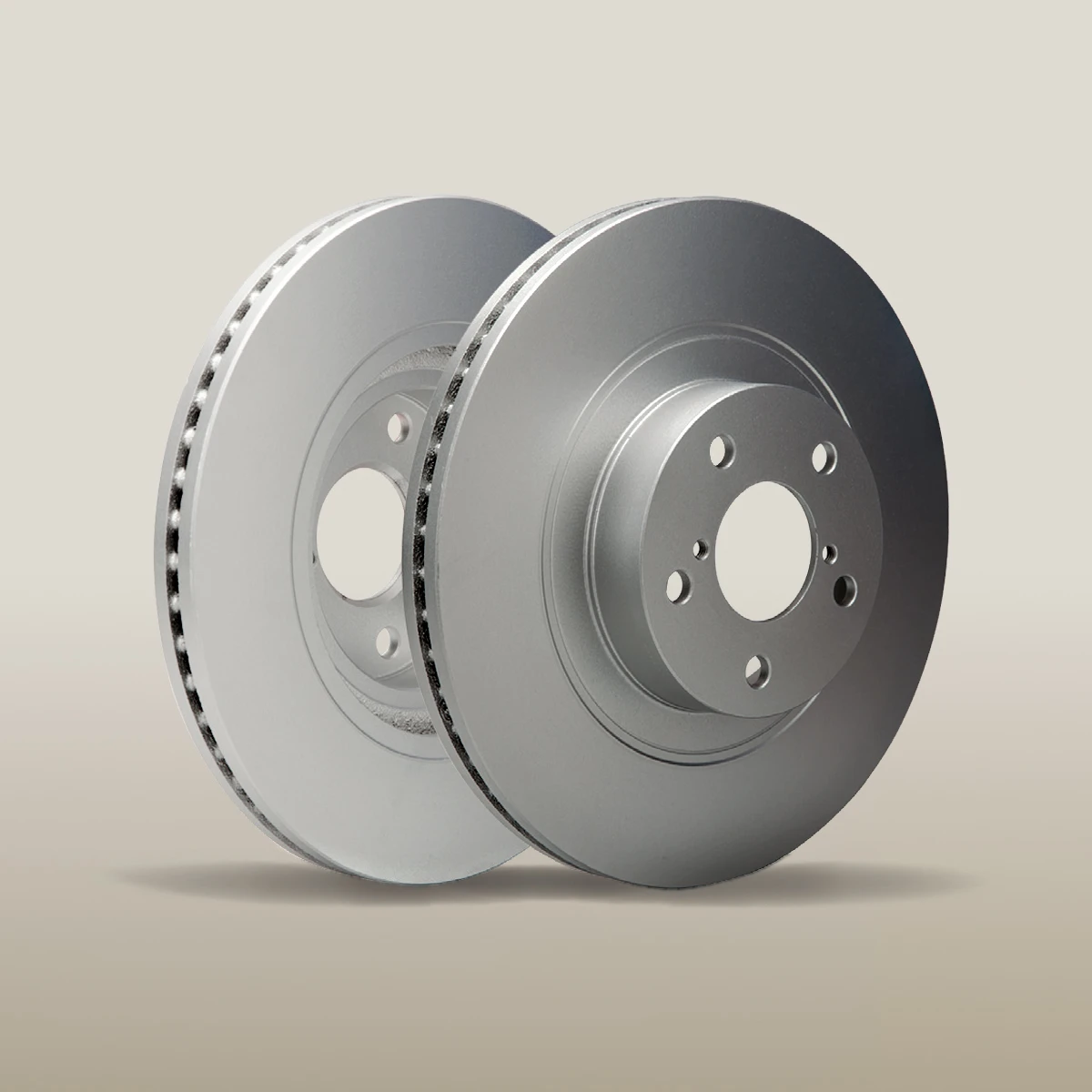 Two brake rotors isolated on a beige background.